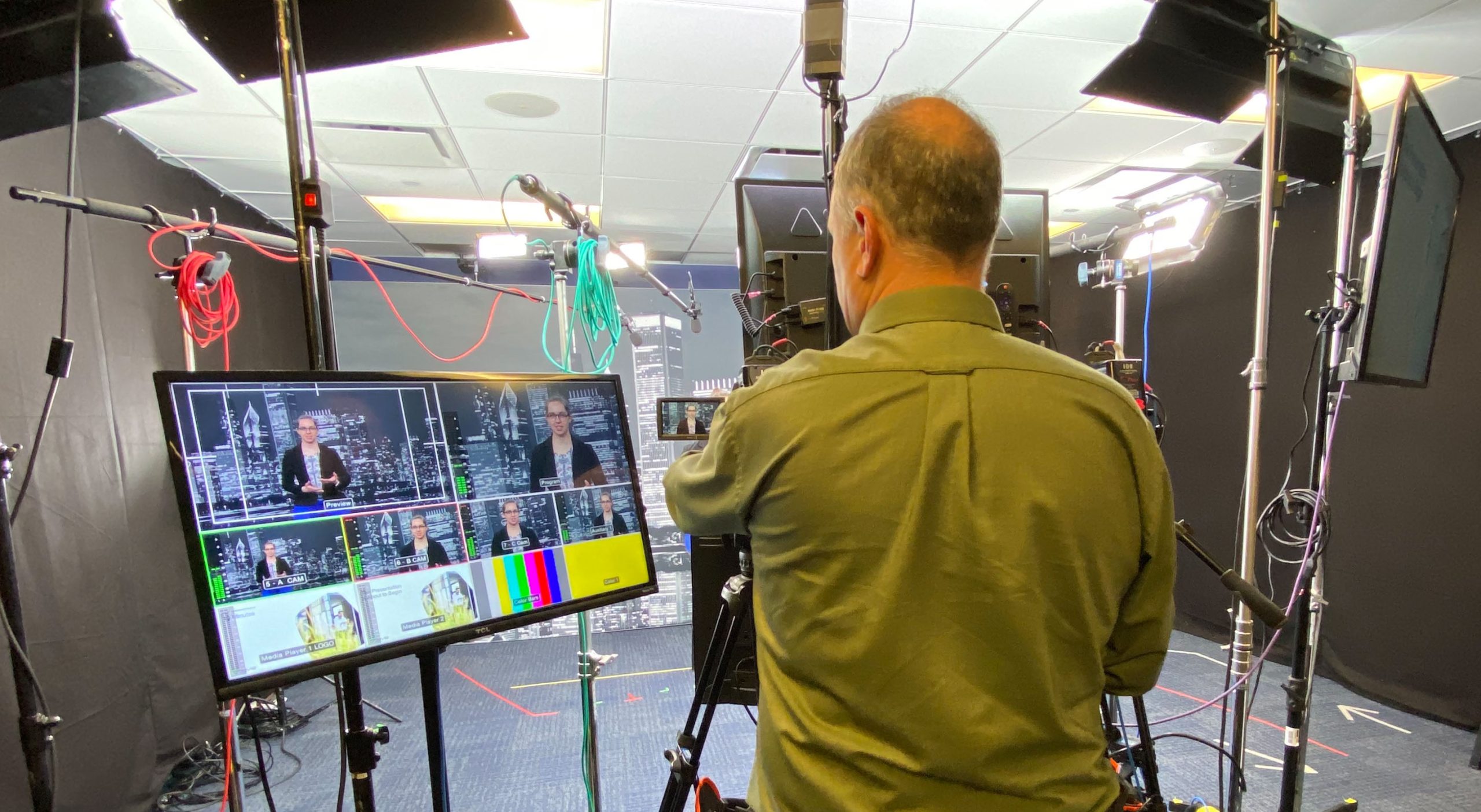 Brella Co-Founder and Senior Event Strategist Mark Mallchok runs the camera while looking at the monitor in a virtual studio setup.