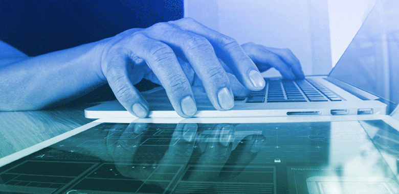 Close up of hands typing on a laptop keyboard.