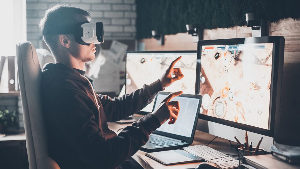 Testing games. young man wearing virtual reality headset and gesturing while sitting at his desk in creative office