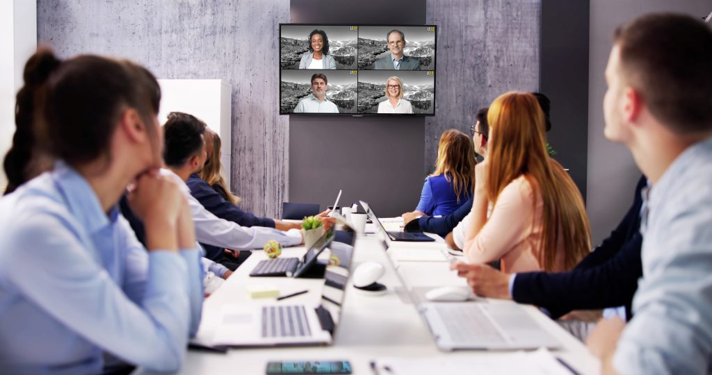 Business professional participating in a meeting, watching a virtual event on an LED screen.