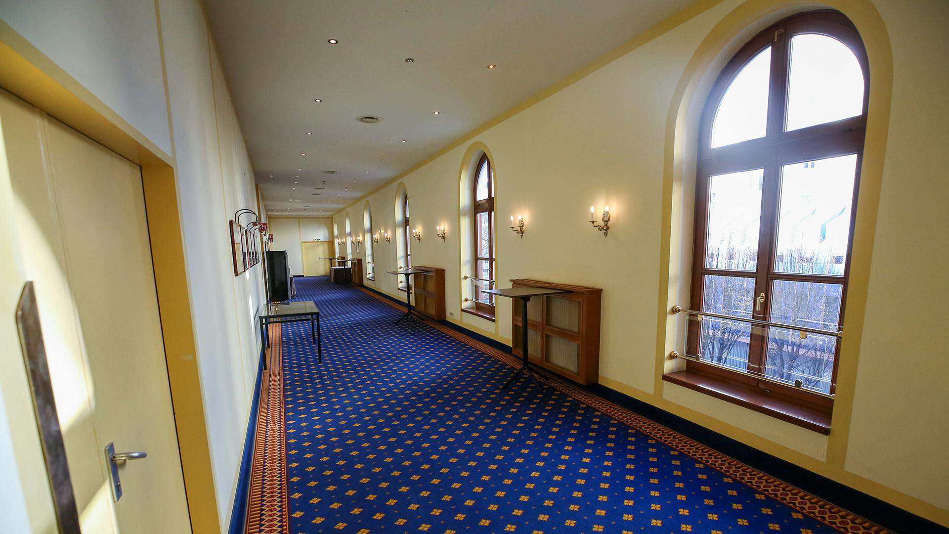 Site survey photo for meeting produced by event management agency Brella, featuring a hotel hallway with tall windows letting in natural light and blue and gold carpeting.