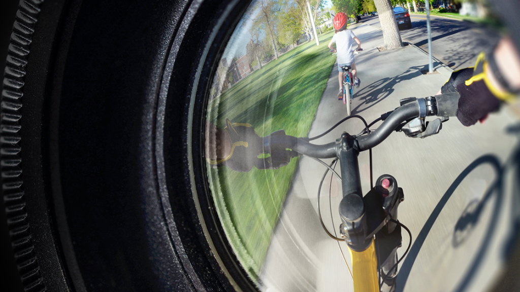 Fisheye lens view of person on bike following child on bike.
