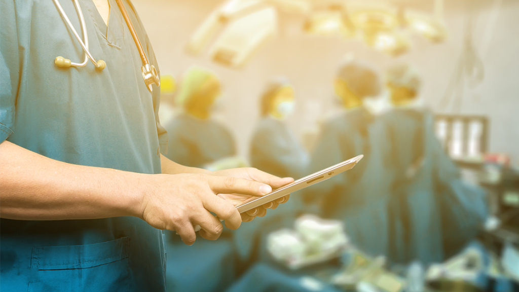 Doctor in scrubs holding a tablet.