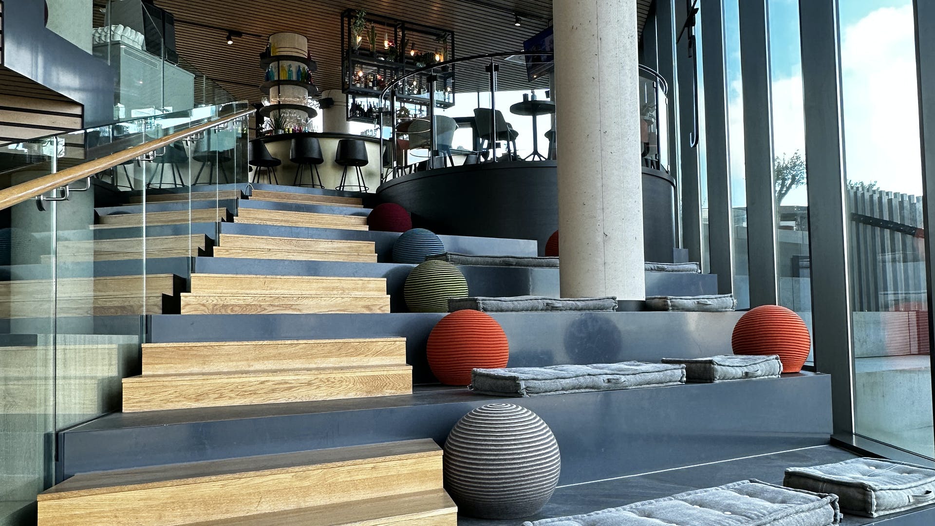 Staircase leading to a mezzanine bar. Exposed support column and colored spheres provide decorative accents.