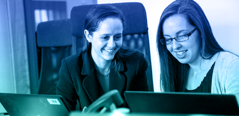 Two female Brella event producers review event presentation designs on laptops.