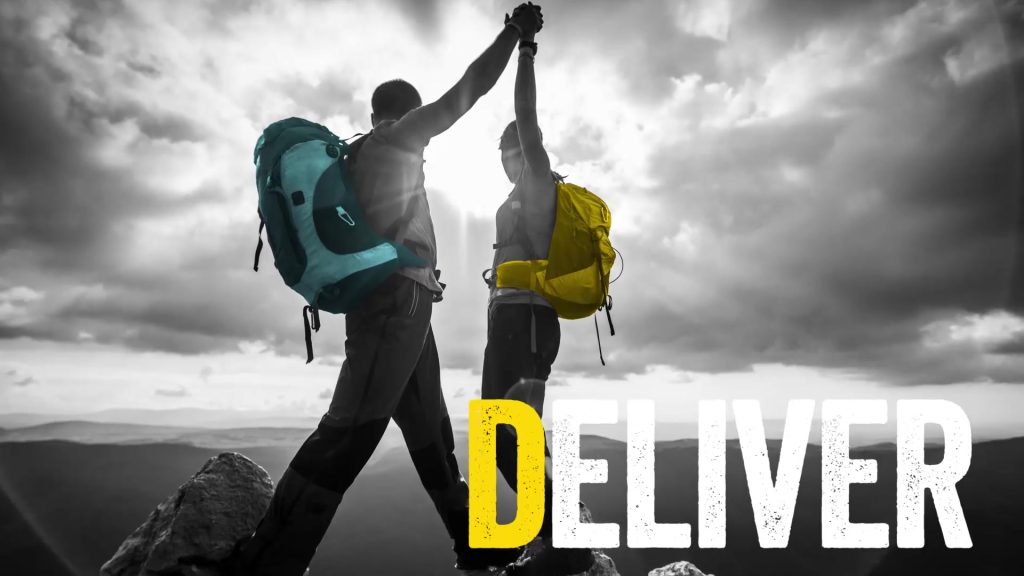 Screen shot from a Brella Productions produced virtual meeting opening video featuring two hikers high-five each other triumphantly with headline DELIVER.