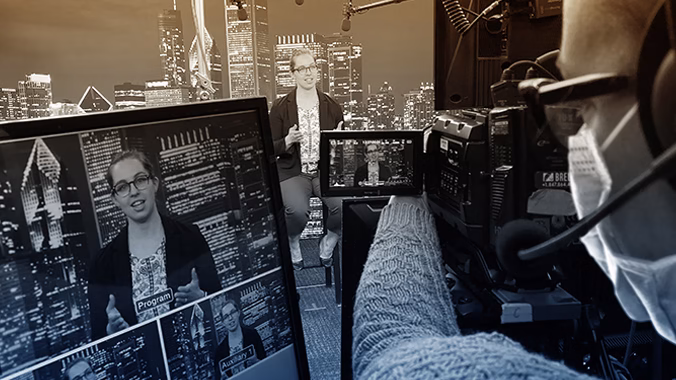In the foreground, a masked Brella event agency camera operator films a female presenter sitting in a studio addressing the camera.